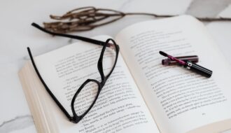 black framed eyeglasses and lipstick on open book
